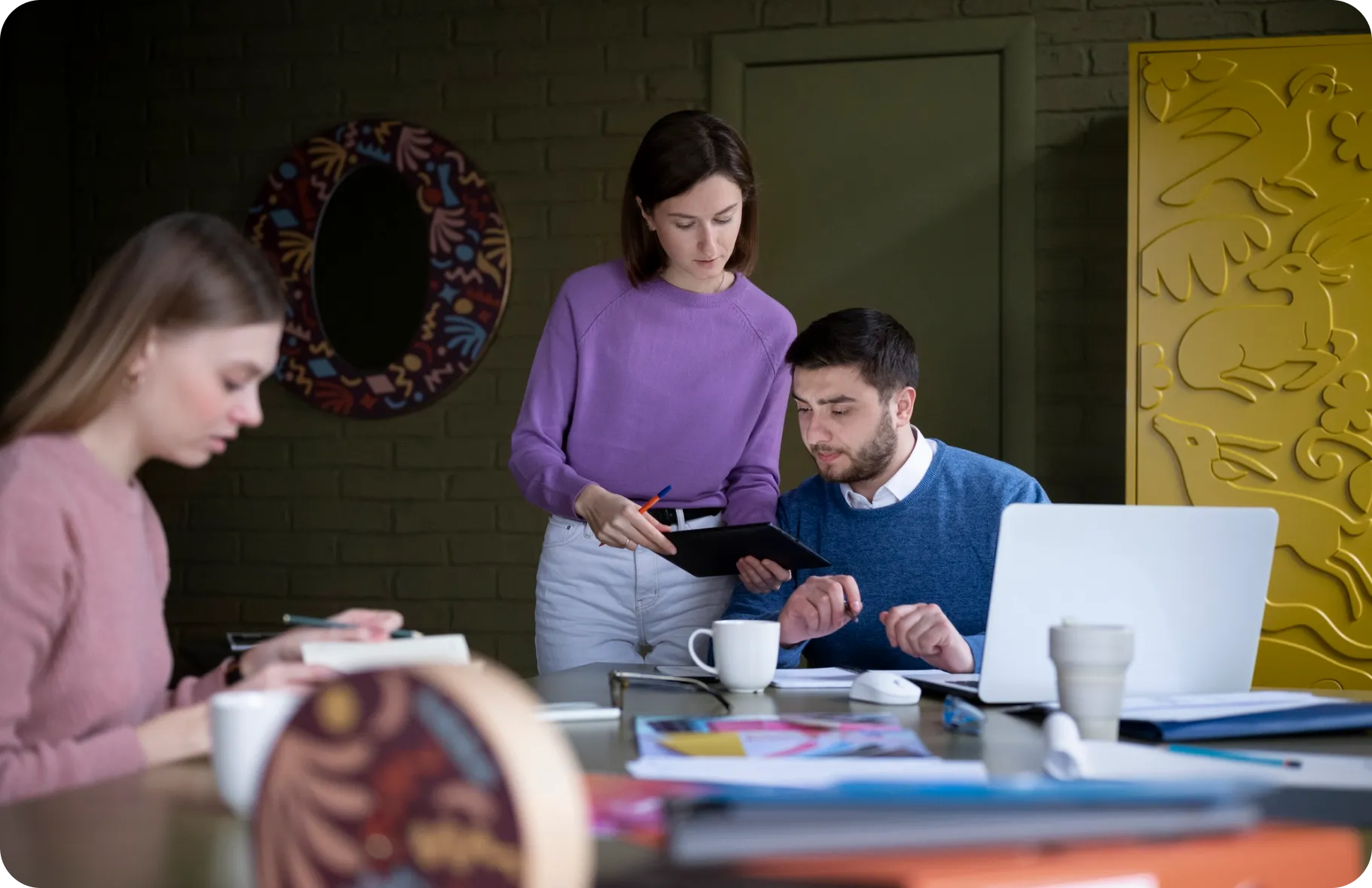a woman standing next to a man looking at a tablet